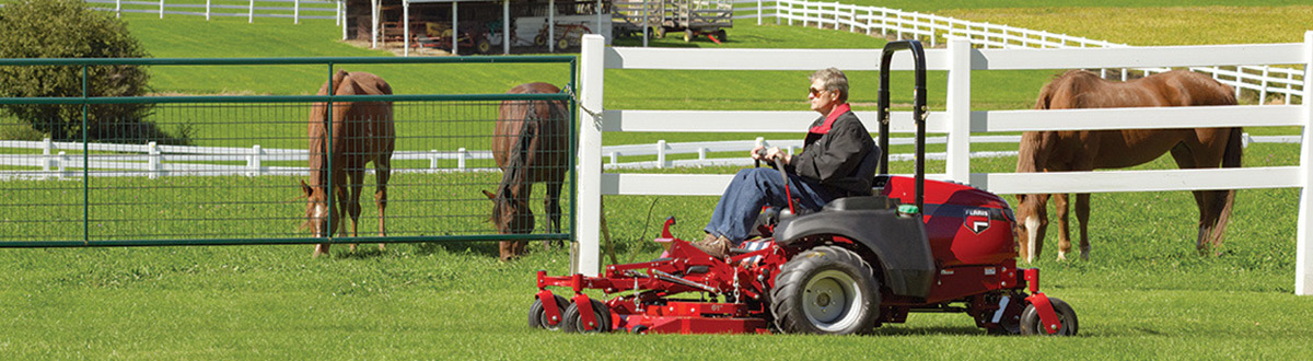 Man in sitting in red Ferris® lawn tractor cutting grass.